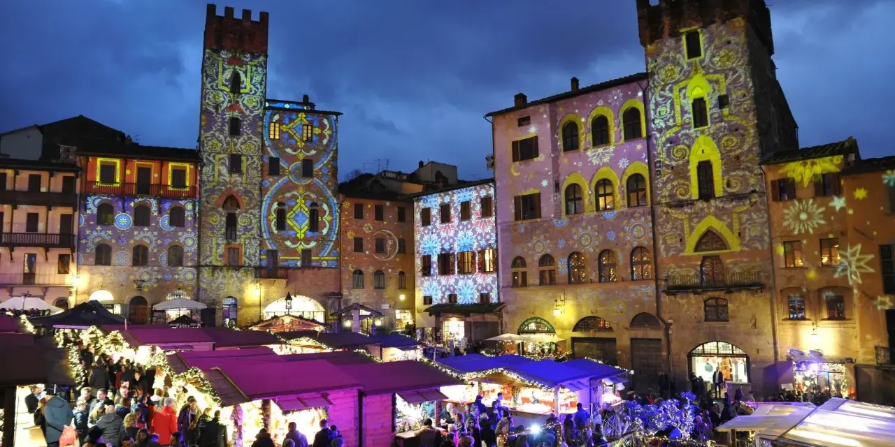 Un magico Arezzo tour: mercatini natalizi illuminati da proiezioni artistiche su torri e palazzi storici.