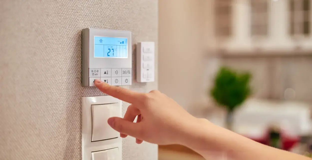 Dito si vede come funziona un termostato manuale: una mano preme un pulsante per regolare la temperatura.