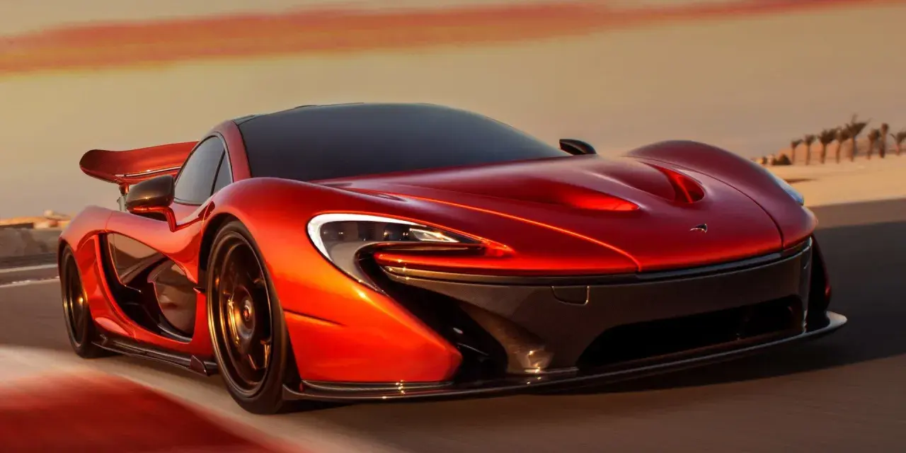 Czerwony McLaren P1 pędzi po pustynnej drodze o zachodzie słońca.