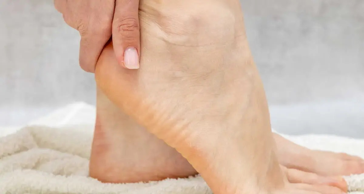 Main d'une personne massant son talon pour hydrater ses pieds.