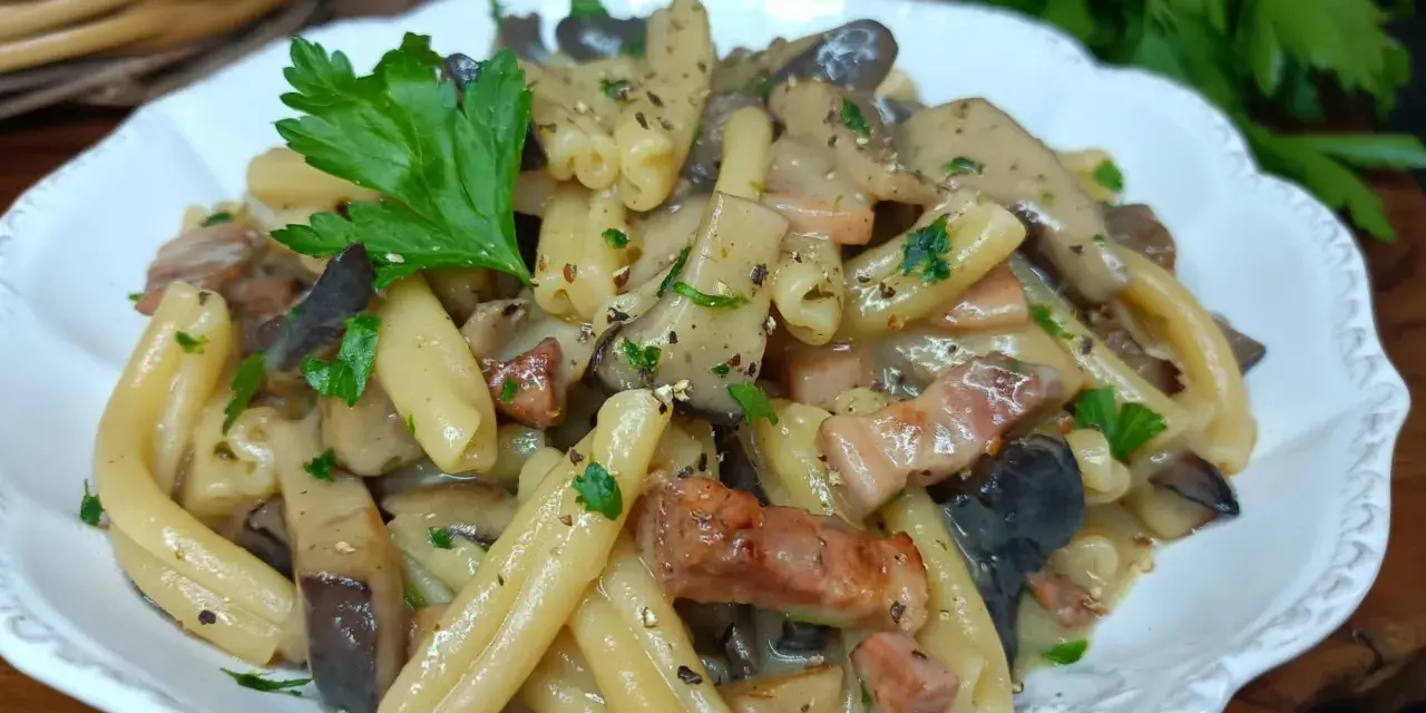 Un piatto invitante di pasta alla boscaiola con funghi e pancetta, guarnito con prezzemolo fresco.