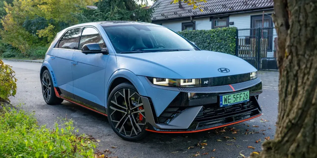 Niebieski Hyundai Ioniq 5 N z czerwonymi akcentami stoi na tle domu i drzew.