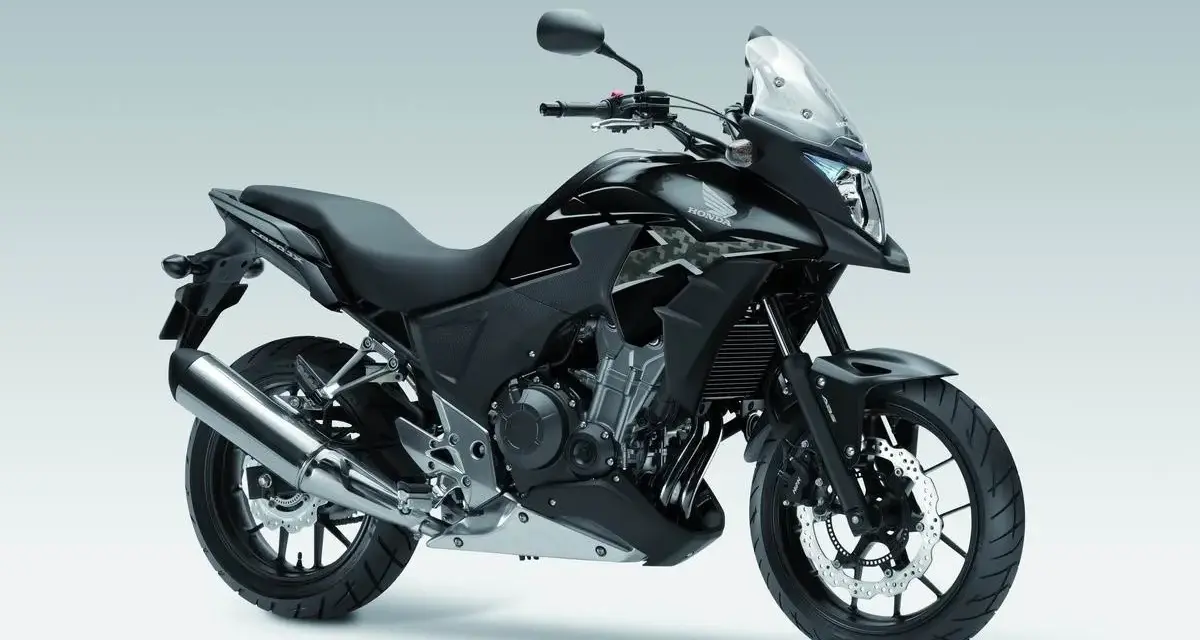 Czarny motocykl Honda CB500X z przyciemnianą szybą i srebrnym wydechem, gotowy na przygodę.