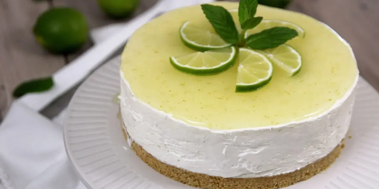 Cheesecake al mojito fresca e profumata, decorata con fettine di lime e menta.