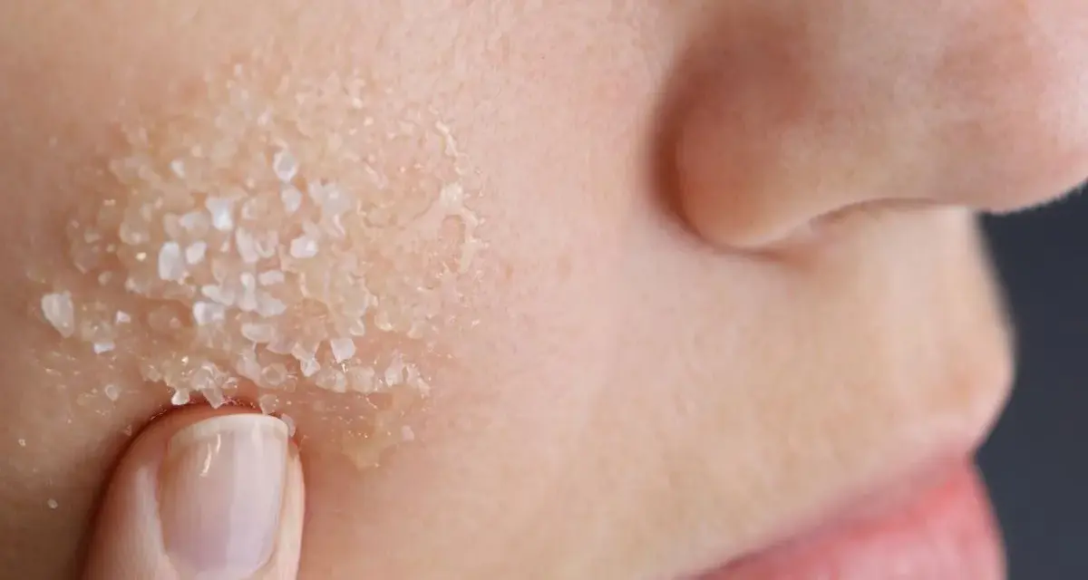 Dito, un dito applica un peeling acido glicolico a casa, con cristalli visibili sulla pelle.