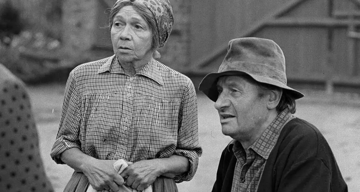 Marta Ławińska w stroju ludowym, obok mężczyzny w kapeluszu, w scenerii wiejskiej.