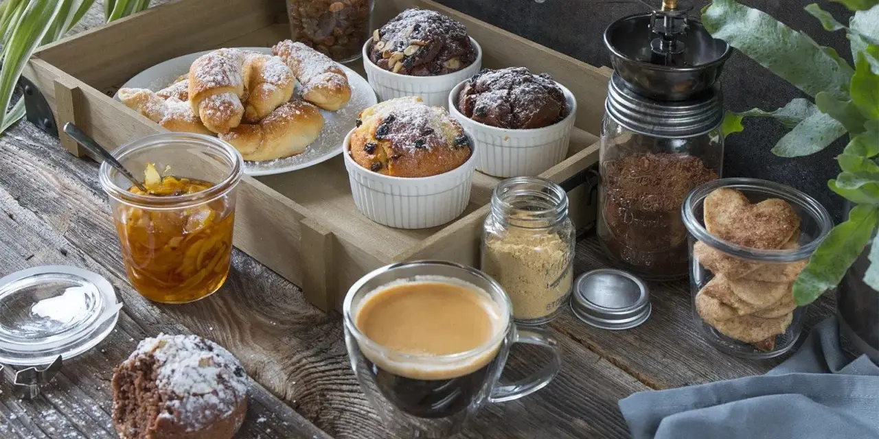 Idealny moment na fika w Szwecji: kawa, rogaliki, muffinki i ciasteczka w kształcie serc na drewnianej desce.
