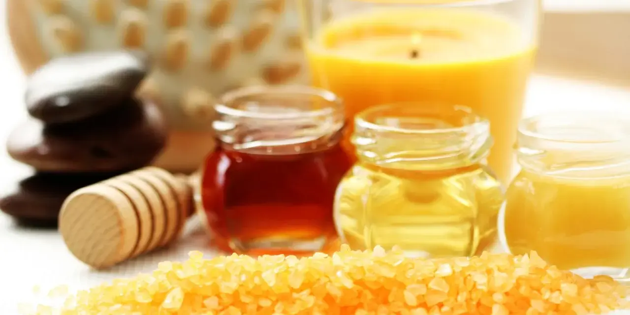 Ingredientes para un exfoliante casero para el cuerpo: sal, miel, aceites y una vela aromática.
