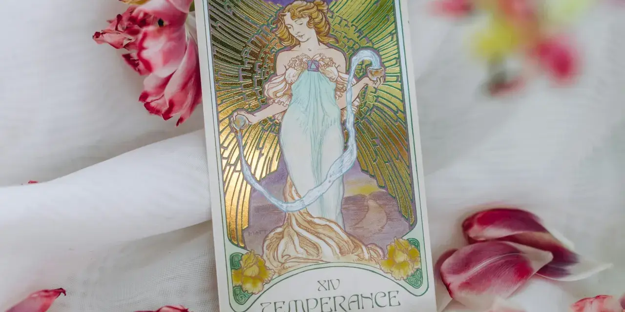 La carta de la templanza tarot, con su figura etérea vertiendo agua, rodeada de pétalos de tulipán rosa y blanco, evoca serenidad y equilibrio.