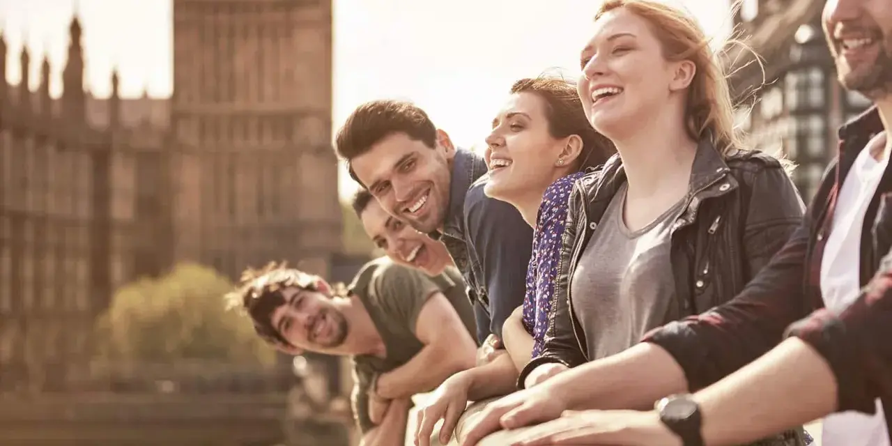 Glückliche Studenten genießen ihr Auslandssemester in England. Im Hintergrund ist das Parlament von London zu sehen.
