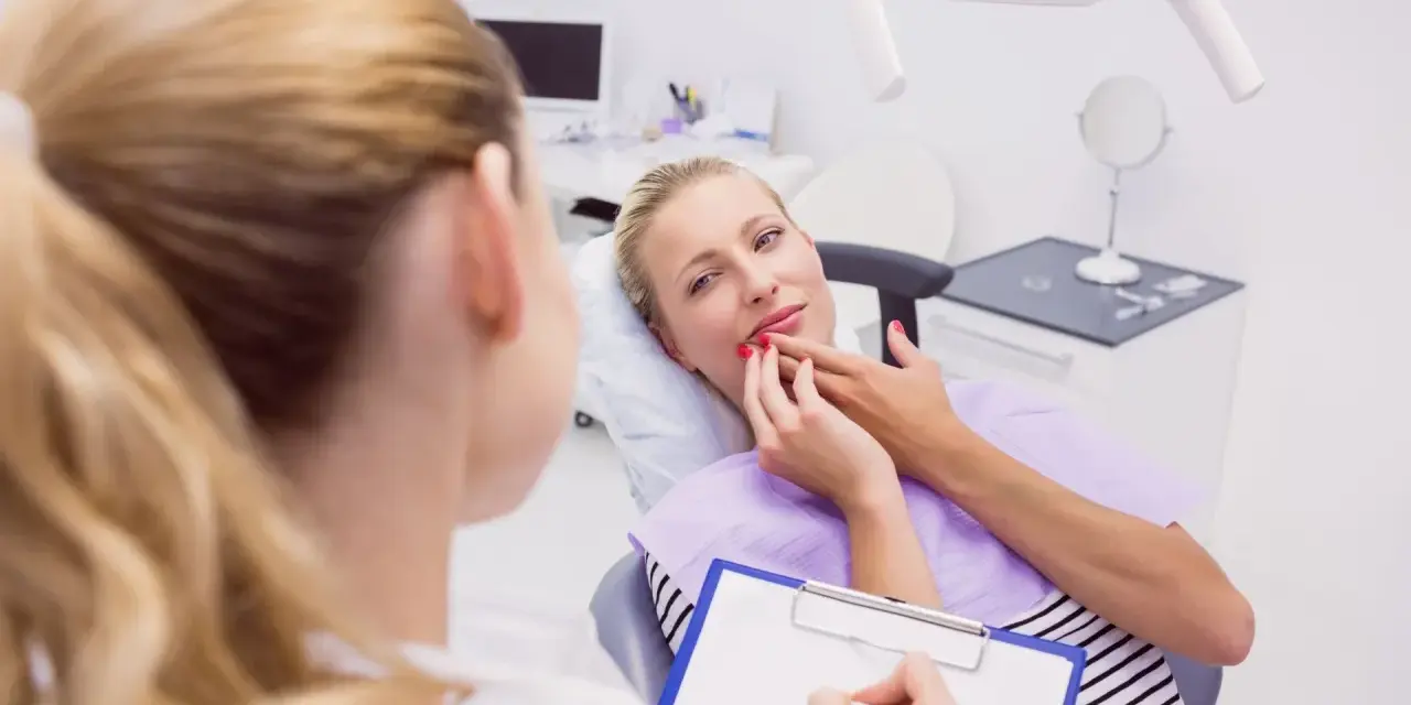 Kobieta w ciąży konsultuje z dentystką co na ból zęba w ciąży. Dentystka notuje na kartce.