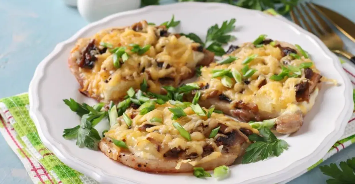 Schab w plastrach pieczony w piekarniku z pieczarkami i serem, posypany szczypiorkiem.