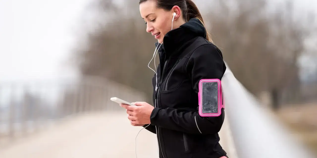 Donna con fascia da braccio rosa per il telefono, ideale per sapere dove mettere il telefono quando si corre.