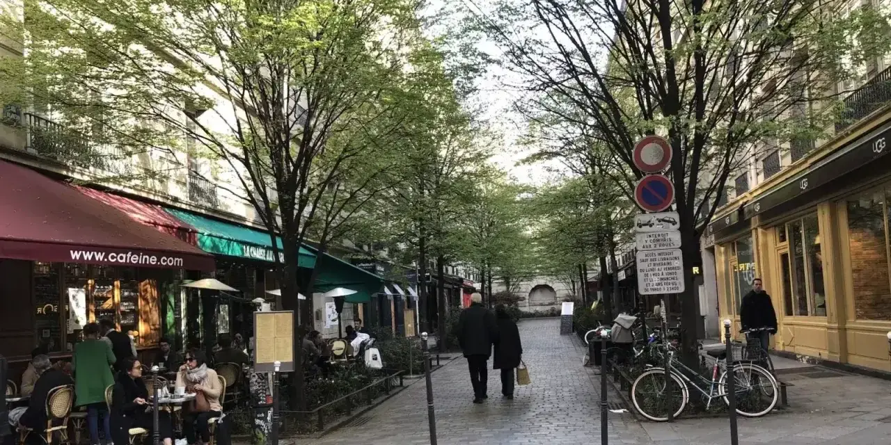Spacerem w le Marais, Paryż, z kawiarniami i ludźmi spacerującymi pod drzewami.