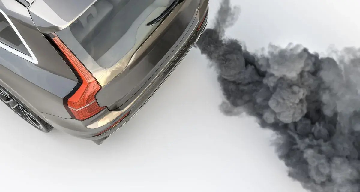 Ein graues Auto stößt beim Gas geben schwarzen Rauch aus dem Auspuff.