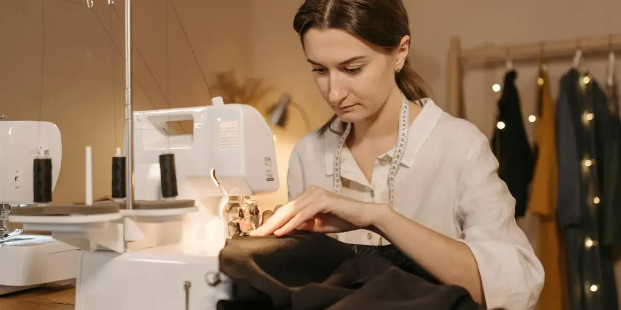 Kobieta szyje na maszynie, przygotowując się do tego, jak wszyć taśmę do firanki.