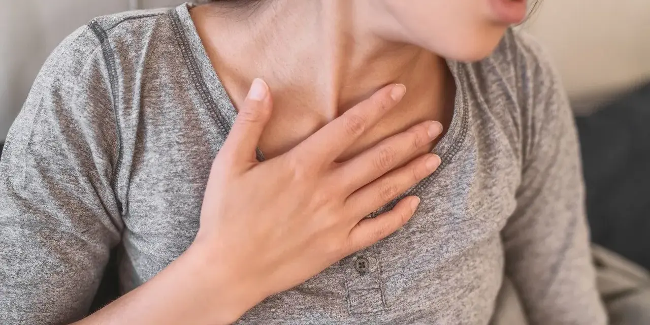 Kobieta z ręką na piersi, czuje ucisk. Czy to globus histericus? Domowe sposoby na ulgę.