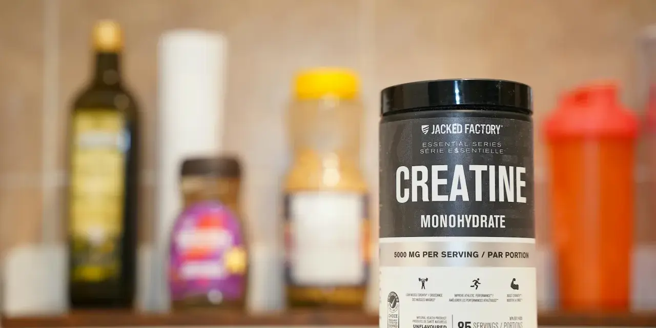 Pojemnik z kreatyną monohydrat Jacked Factory na tle innych suplementów.