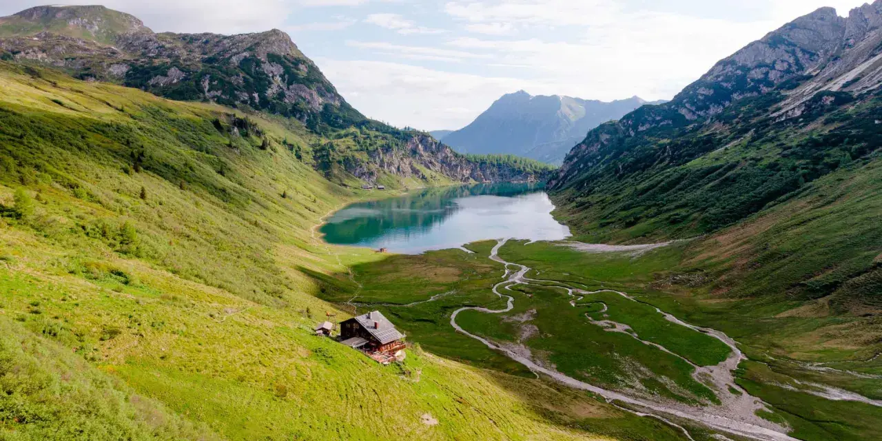 Idyllischer Salzburg See, umgeben von grünen Bergen. Eine Hütte am Hang lädt zum Verweilen ein.