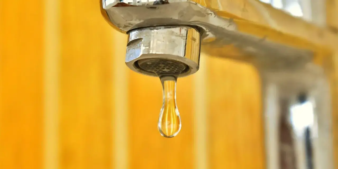 Goccia d'acqua fredda dal rubinetto cromato. La caldaia non esce acqua calda, un problema comune in casa.