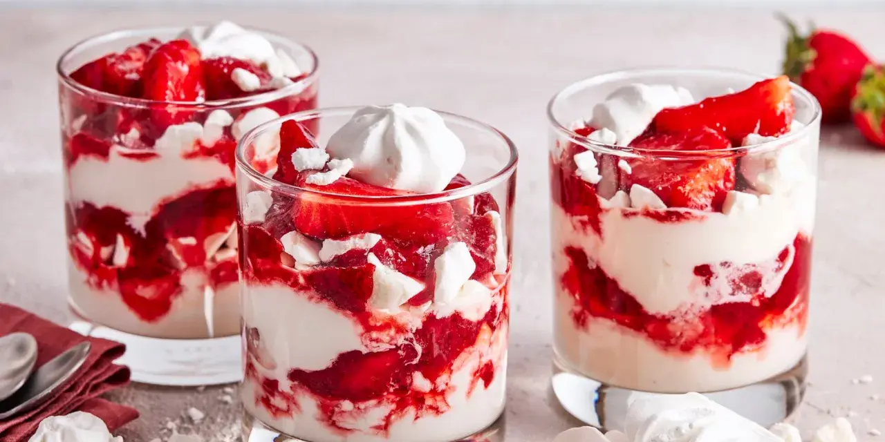 Drei Gläser mit Eton Mess: geschichtete Erdbeeren, Sahne und zerbrochene Baiser-Stücke.