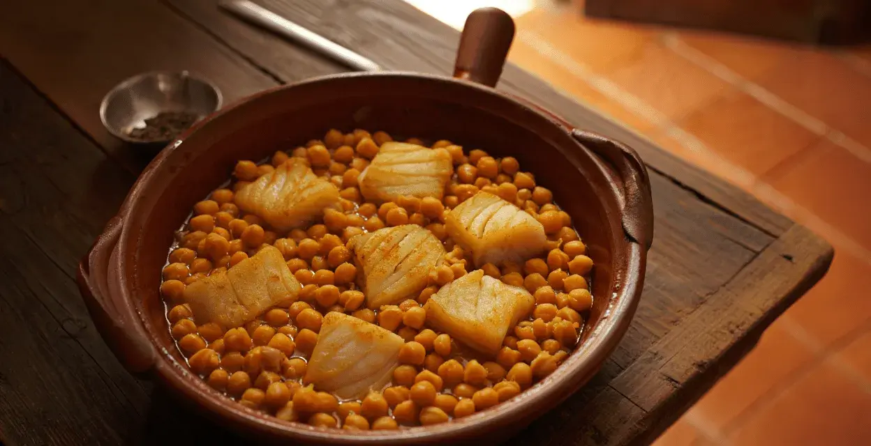 Guiso de garbanzos con trozos de bacalao en cazuela de barro.