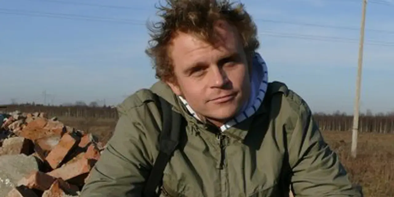 Piotr Rogucki, w otoczeniu gruzu, z charakterystyczną fryzurą, jakby inspirowany swoimi utworami.