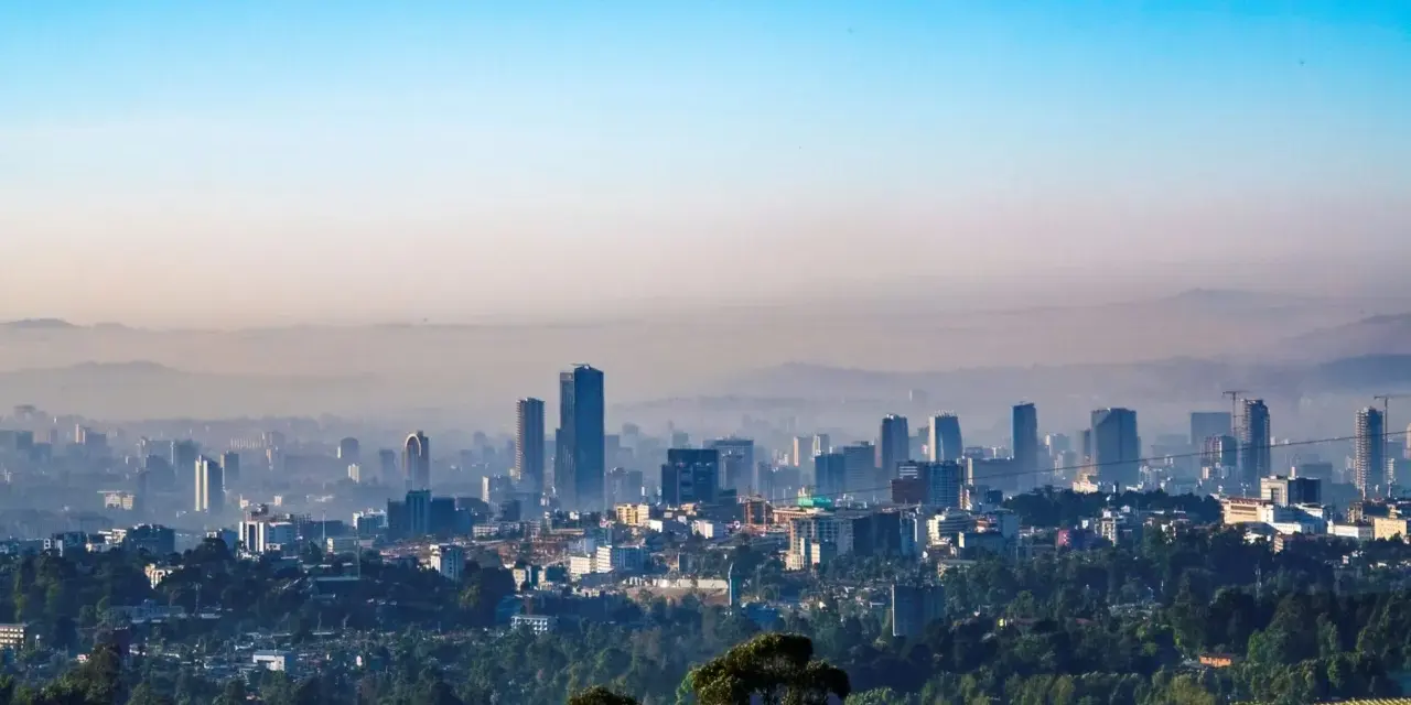Widok na rozległe miasto Addis Abeba, zdominowane przez nowoczesne wieżowce i otoczone zielenią.