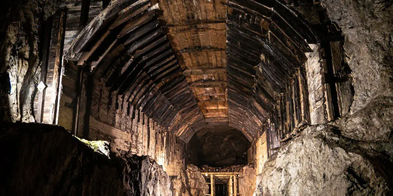 Wnętrze tunelu w kompleksie Riese, gdzie kryją się tajemnice wojny. Drewniane wsporniki i skalne ściany tworzą mroczny korytarz.