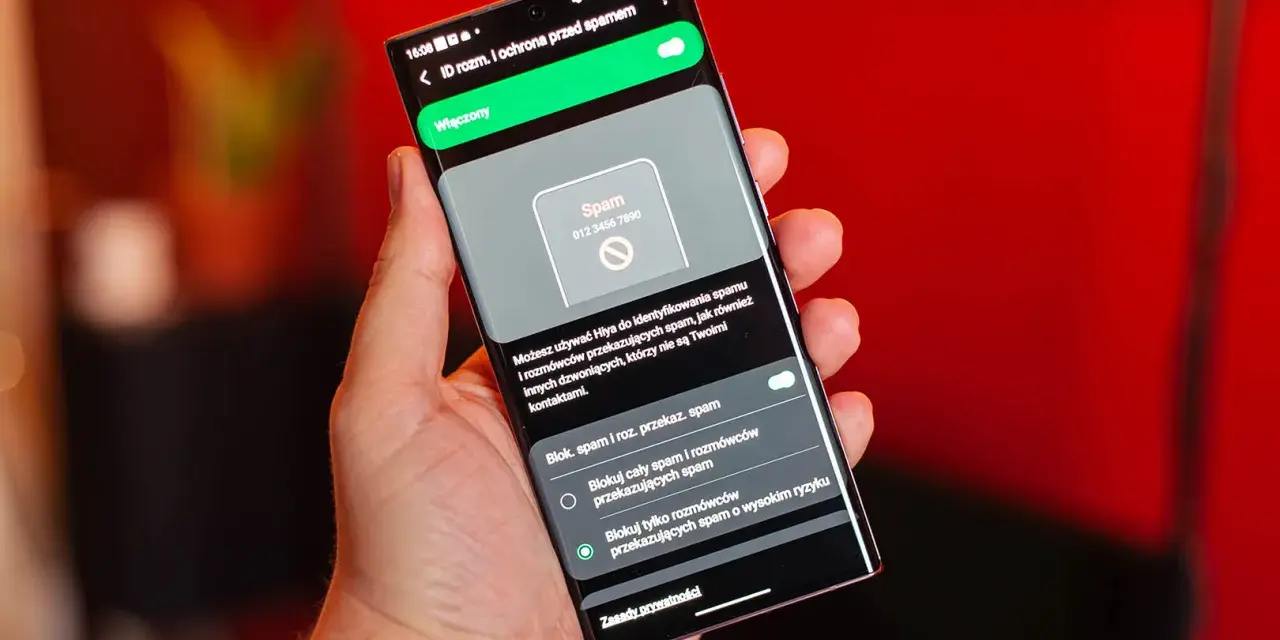 Dłoń trzyma smartfon z włączoną ochroną przed spamem. Ekran pokazuje powiadomienie o potencjalnym spamerze, gdy dzwonią z laboratorium.