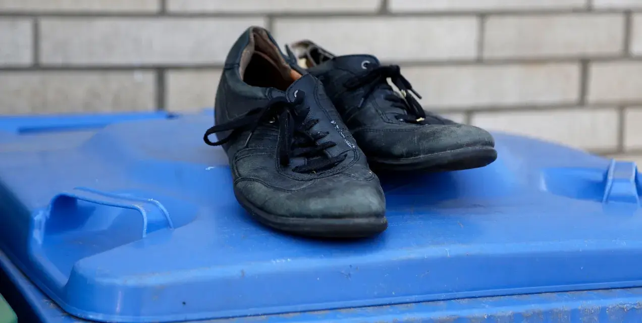 Stare buty na niebieskim koszu na śmieci. Zastanawiasz się, gdzie wyrzucać stare buty? To miejsce może być odpowiedzią.