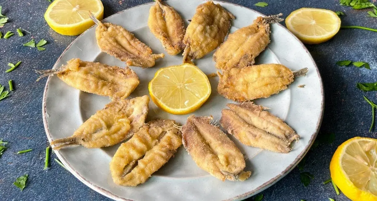Deliciosos boquerones al limón, crujientes y dorados, servidos en un plato con rodajas de limón y perejil fresco.