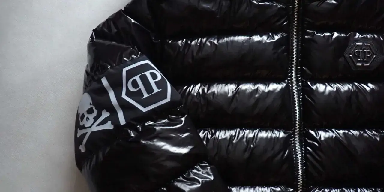 Błyszcząca, czarna kurtka Philipp Plein z futrzanym kapturem i białym logo na rękawie.