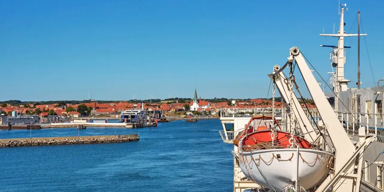 Widok z promu na Bornholm. Widać port, miasteczko z czerwonymi dachami i kościołem, a na pierwszym planie łódź ratunkową.