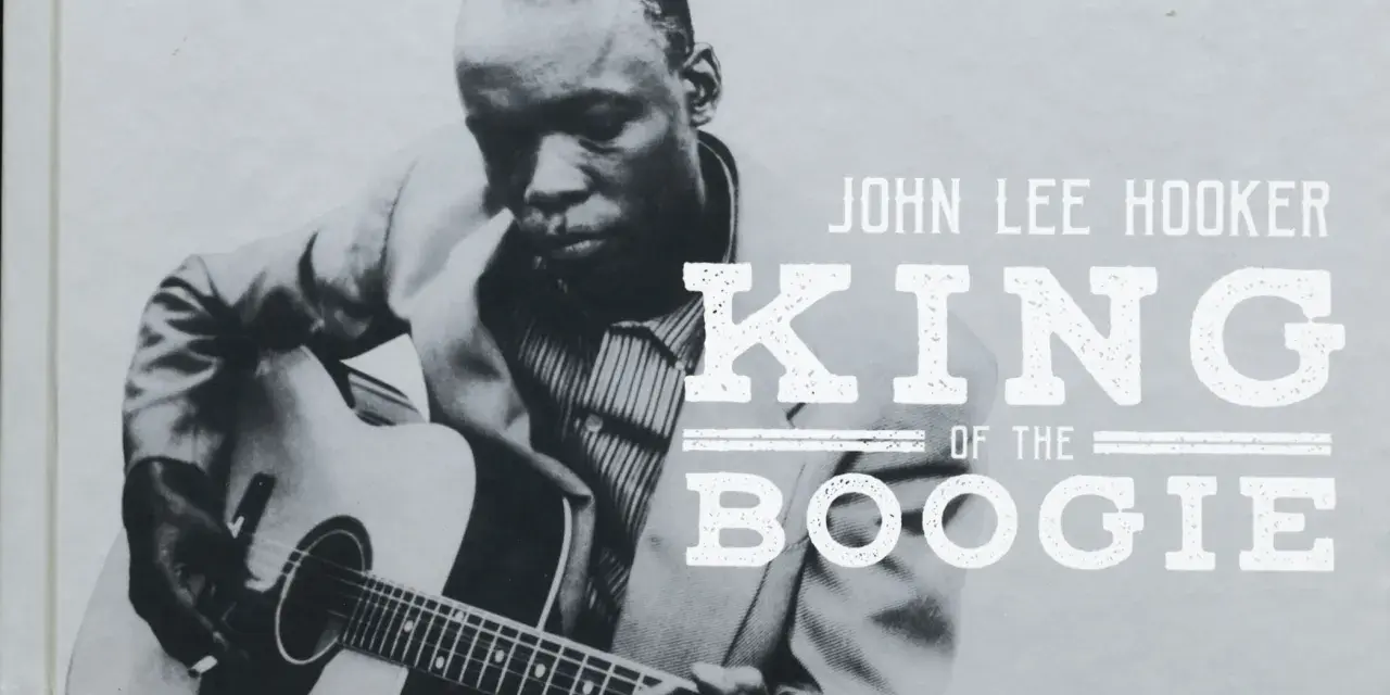 John Lee Hooker, King of the Boogie, spielt Gitarre. Sein Blick ist konzentriert, während seine Finger über die Saiten gleiten.