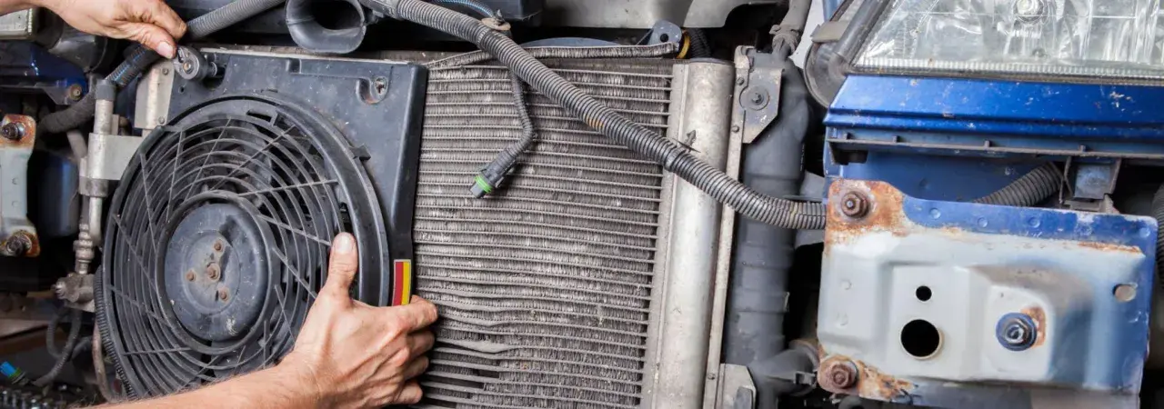 Mechanic inspects car's condenser, noting bent fins and corrosion, common symptoms of a bad condenser.