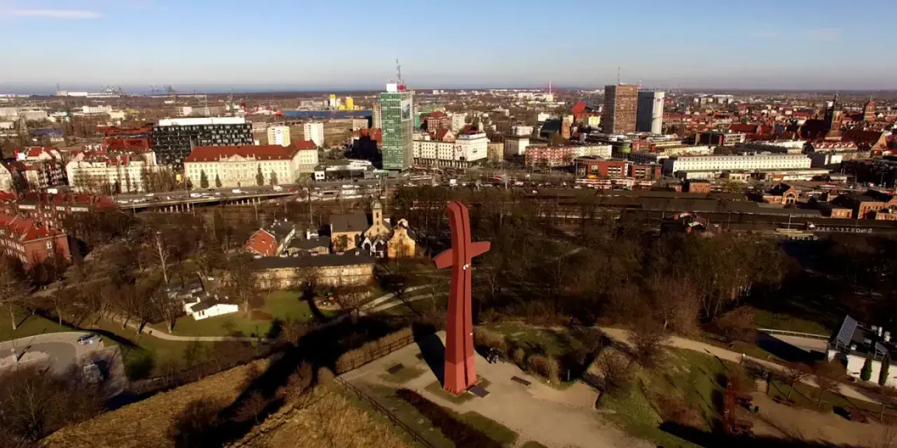 Góra Gradowa z czerwonym monumentem w kształcie krzyża na tle panoramy miasta.