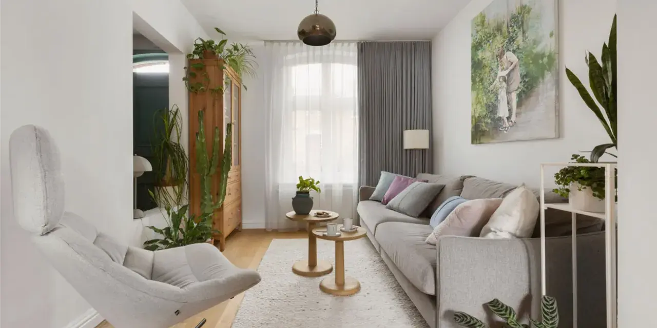 Przytulny salon w domu z szarą kanapą, wygodnym fotelem i mnóstwem zielonych roślin.