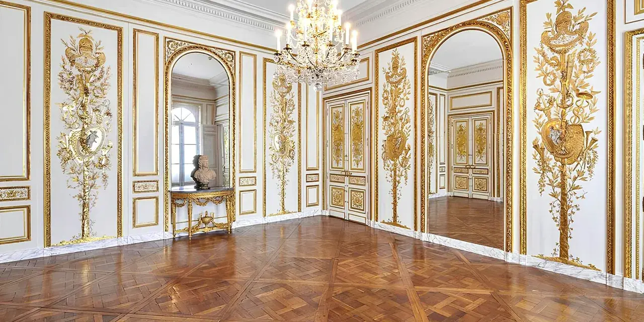Salón dorado del museo Carnavalet, con suelo de parqué, candelabro de cristal y ornamentación dorada en las paredes.