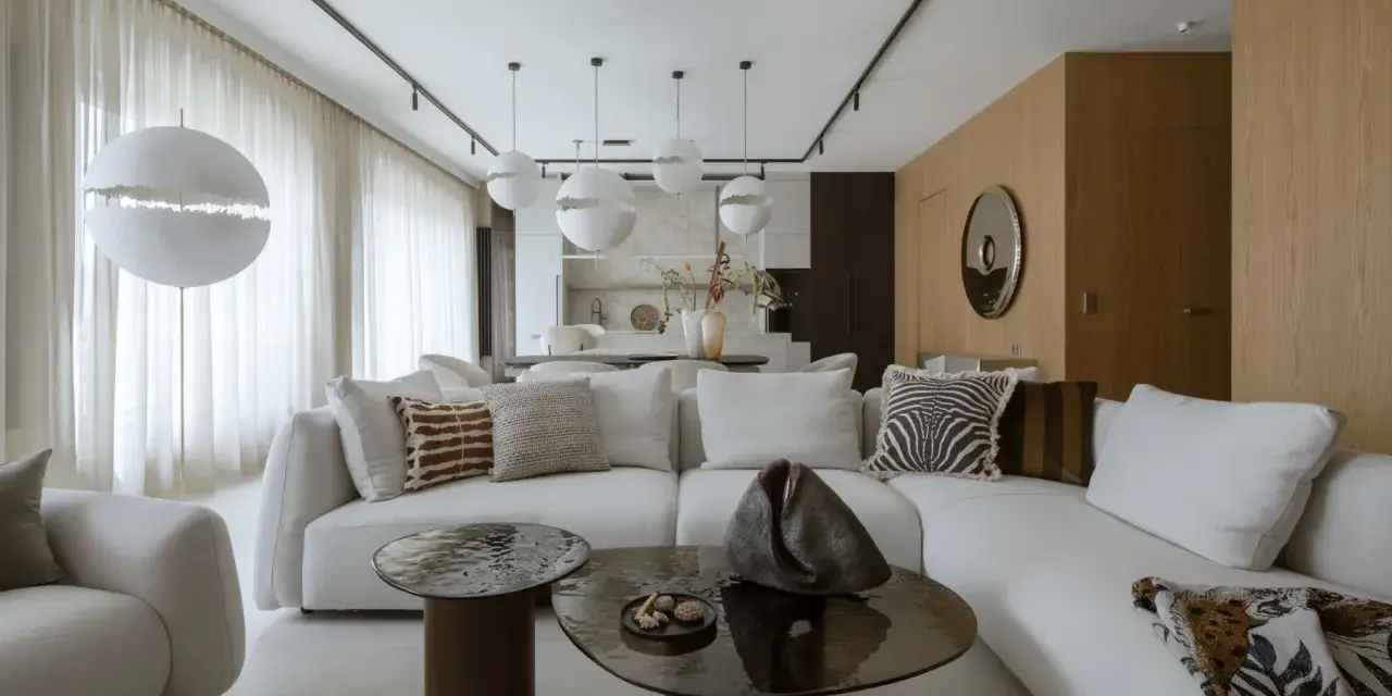 Nowoczesny projekt mieszkania z białą sofą, okrągłymi stolikami i designerskimi lampami.