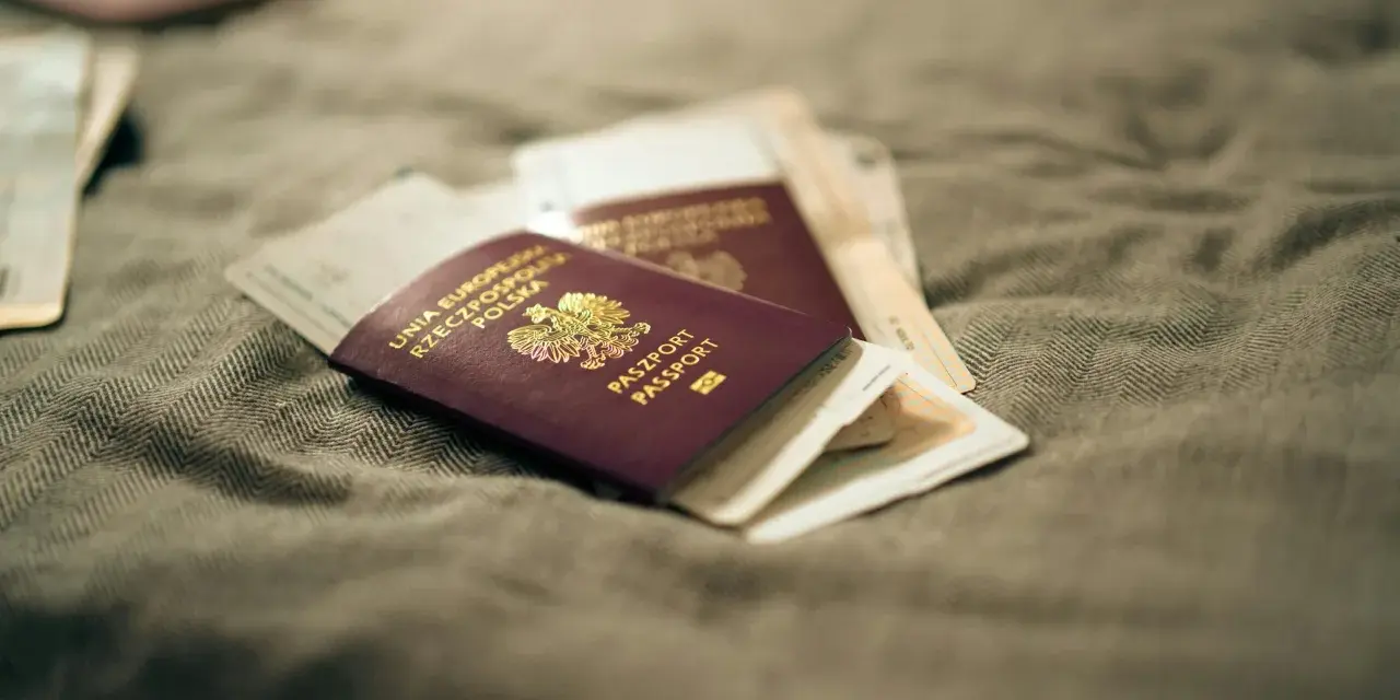 Kilka paszportów leży na szarym materiale. Zastanawiasz się, ile czeka się na paszport w Polsce?