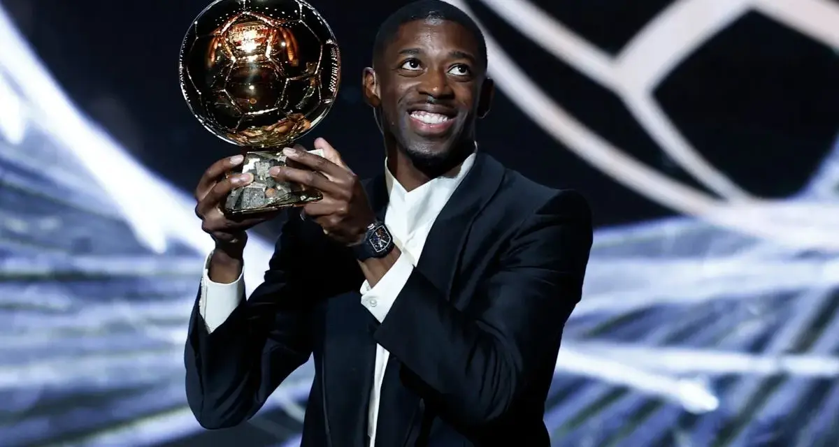 Piłkarz Ousmane Dembélé trzyma Złotą Piłkę na scenie.