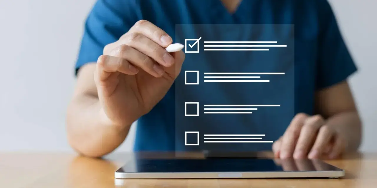 Dłoń zaznacza ptaszkiem pierwszy element na liście kontrolnej wyświetlanej na ekranie tabletu.