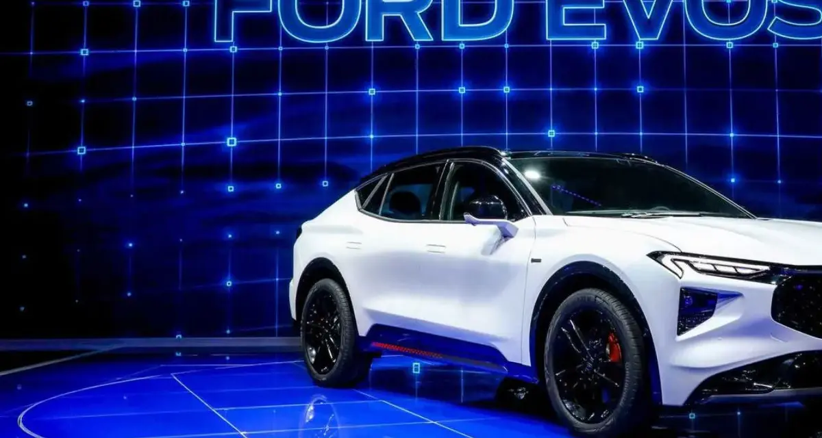 Biały Ford Evos na niebieskim, futurystycznym tle z siatką. Elegancka linia nadwozia i sportowe detale podkreślają jego nowoczesny charakter.