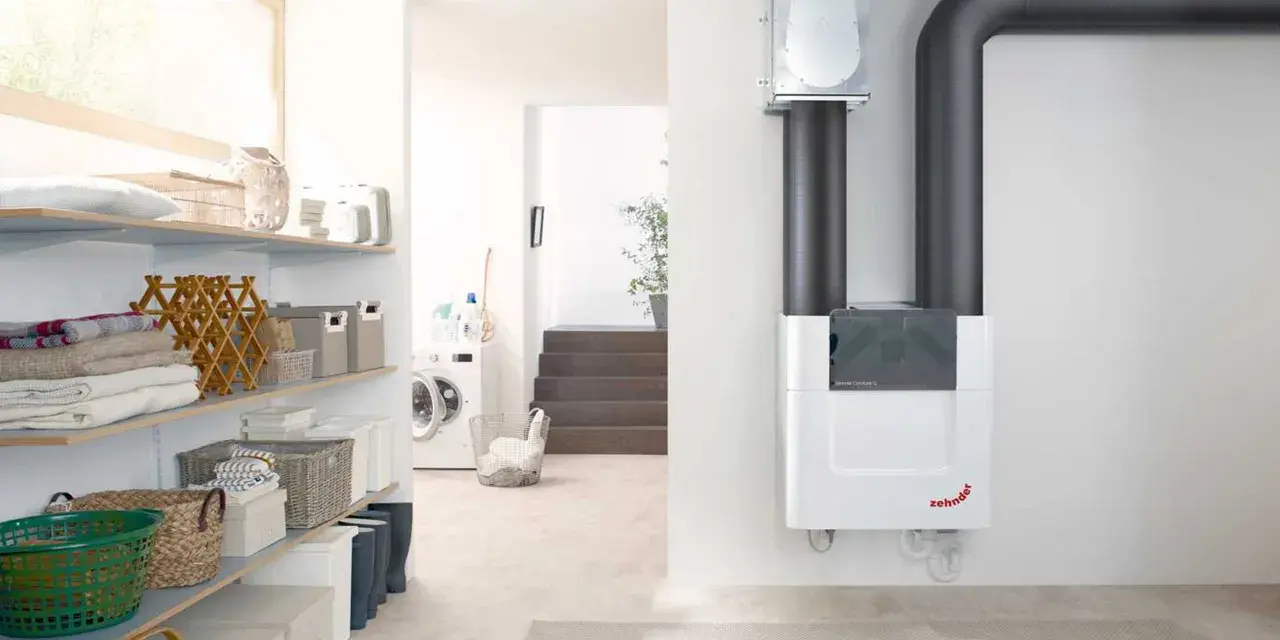 Sistema de ventilación con recuperación de calor Zehnder ComfoAir Q, con tuberías grises y un diseño blanco moderno.