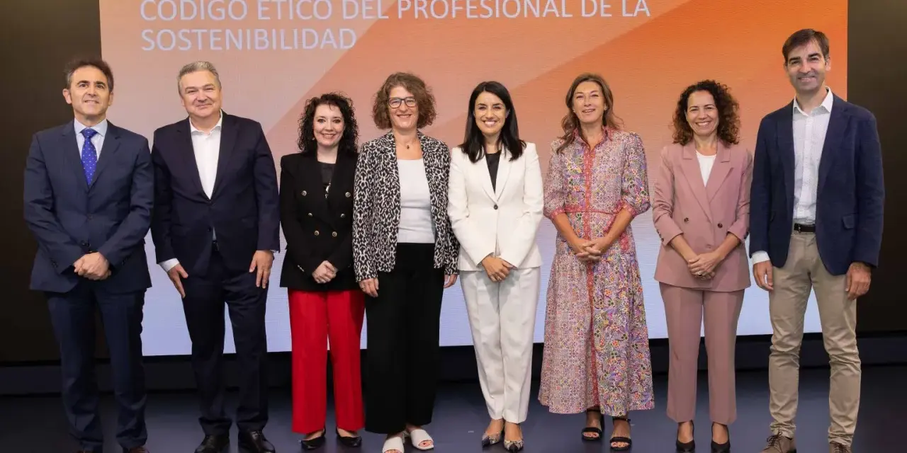 Presentación del código de ética de una empresa. Un grupo de siete profesionales posa en un escenario con un fondo naranja y blanco.