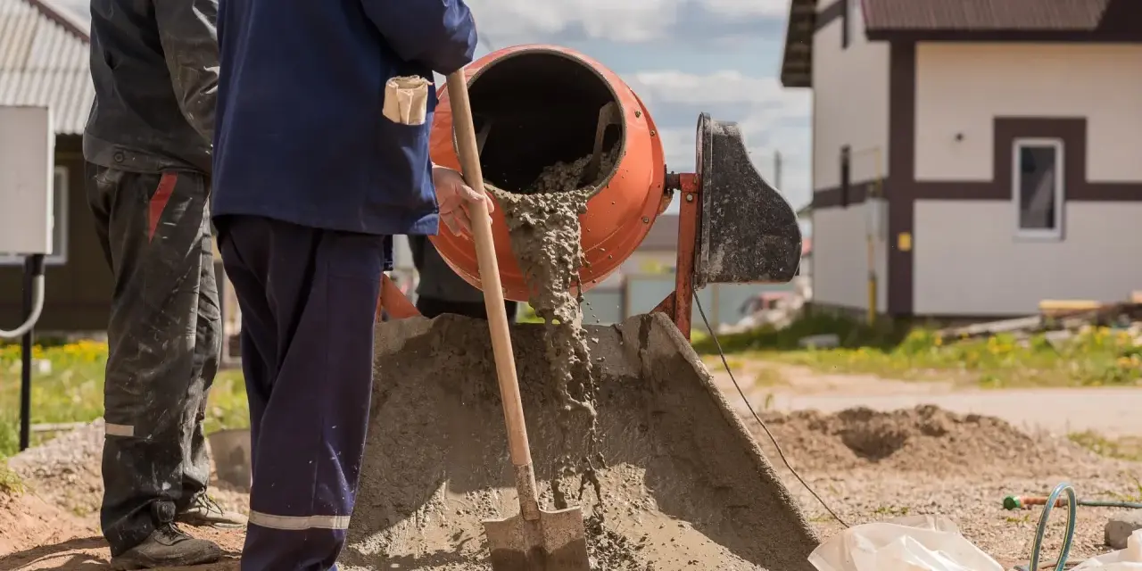 Pracownicy budowlani wylewają beton z betoniarki. Pytanie: ile cementu na betoniarkę 200?