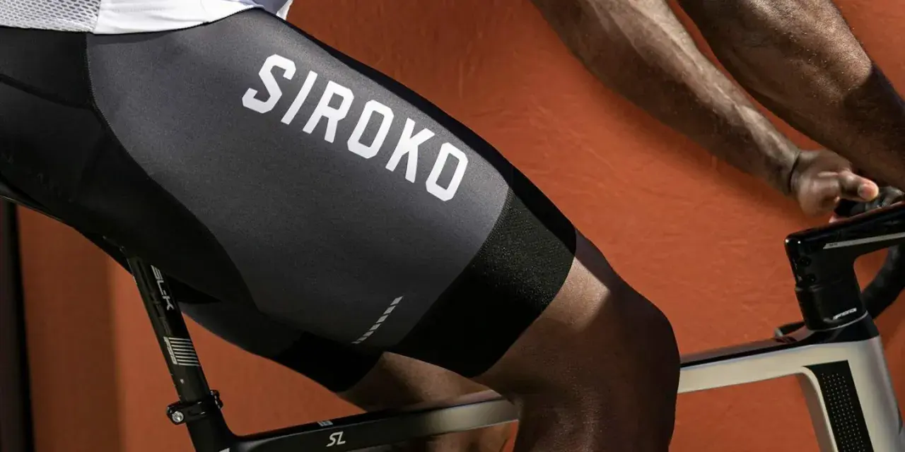 En cyklist med synliga cykling muskler på benen, klädd i svarta cykelbyxor med texten "SIROKO".