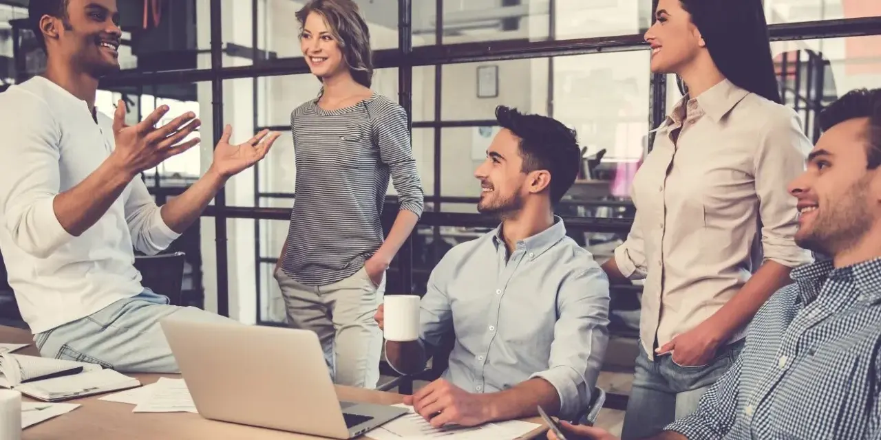 Un gruppo di persone in un ufficio moderno discute animatamente. I colleghi non sono amici, ma lavorano insieme con professionalità.