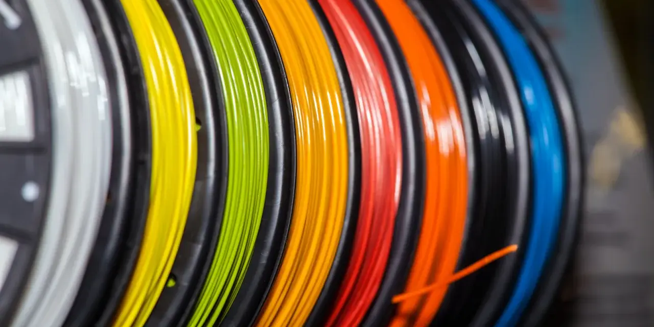 Kolorowy filament do druku 3D, nawinięty na szpulki. Zastanawiasz się, filament co to? To materiał do tworzenia trójwymiarowych obiektów.